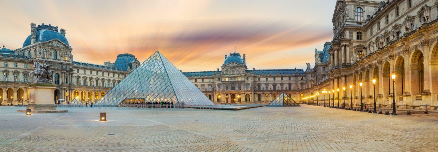 View of the Louvre Pyramid in the Cour Napoléon, with the surrounding palace façades and illuminated arcades at sunrise.