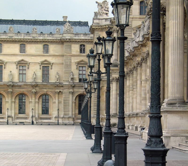 View of the Louvre’s eastern colonnade in Paris, with Corinthian columns and a row of black lampposts leading toward the palace façade