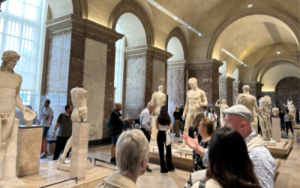 Greek and Roman Antiquities Gallery — Denon Wing Ground Floor, Louvre Museum Greek and Roman sculpture gallery, Louvre Museum Denon wing — marble figures on pedestals in a vaulted hall with red antique marble columns and arched windows, visitors circulating among the works