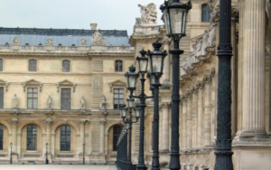 laternen louvre Cour Napoléon, Louvre Museum, Paris — cast iron ornamental lamp posts in perspective line along the Richelieu wing facade, allegorical sculptures visible on the roofline, empty courtyard in morning light