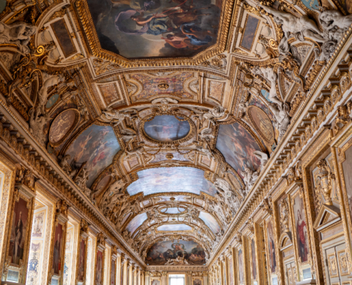 View of the Galerie d’Apollon at the Louvre. Source: Adobe Stock View of the Galerie d’Apollon at the Louvre in Paris, showing the richly decorated vaulted ceiling, gilded carvings, and painted panels