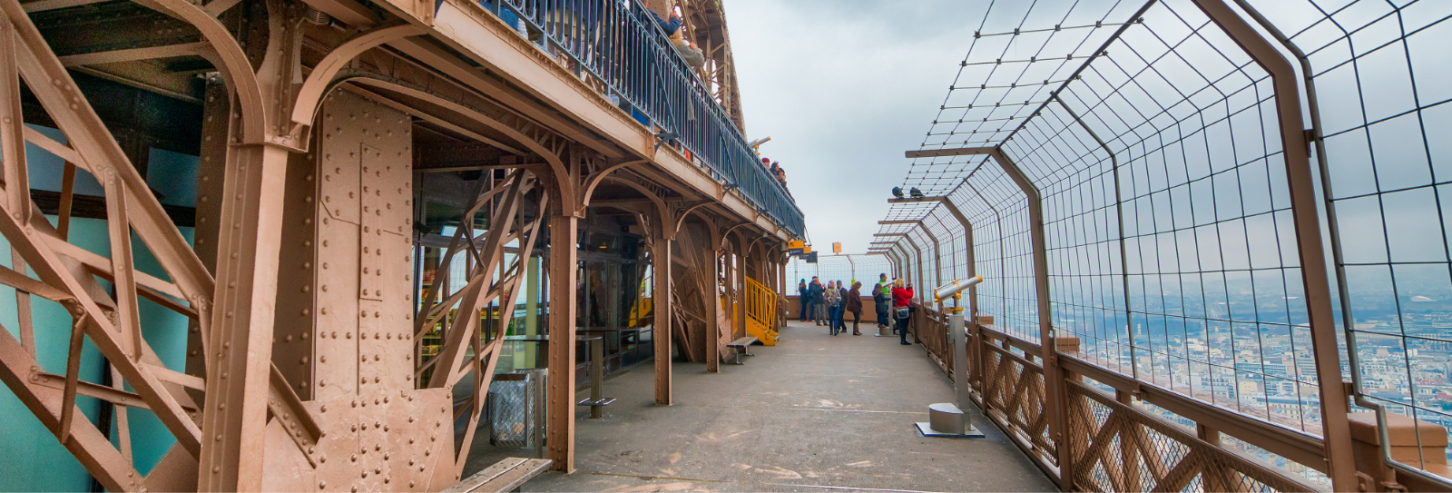 Adobe Stock Eiffel Tower Upper Observation Deck in Daylight Adobe Stock daytime view of the Eiffel Tower upper observation deck with iron structure, safety fencing, and visitors overlooking Paris