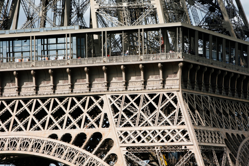Close view of the Eiffel Tower’s first floor, showing the iron structure, enclosed viewing area, and architectural details of the platform.