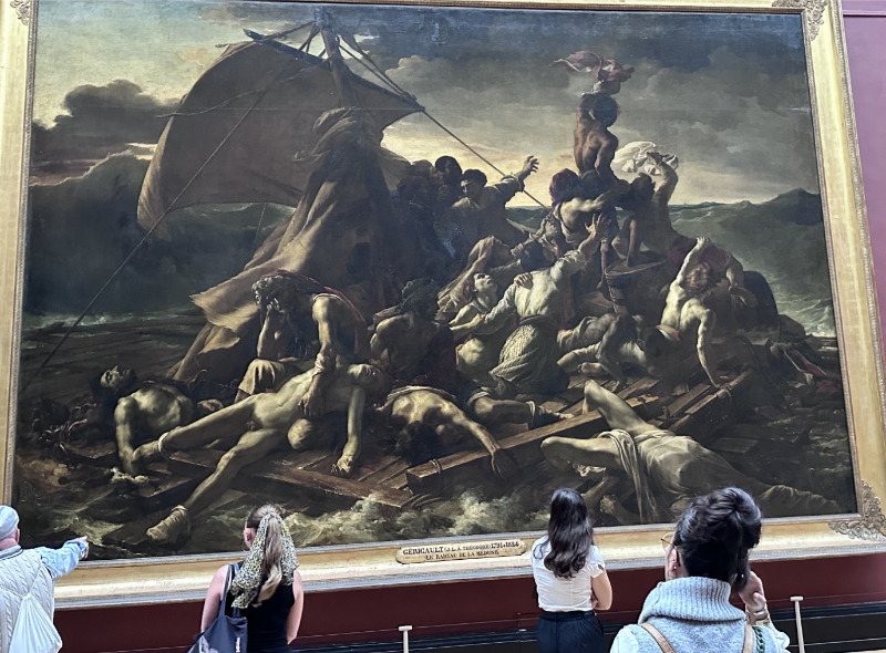 View of The Raft of the Medusa displayed at the Louvre, showing Géricault’s monumental shipwreck scene in a large gilded frame against deep red gallery walls, with visitors gathered in front of the painting.